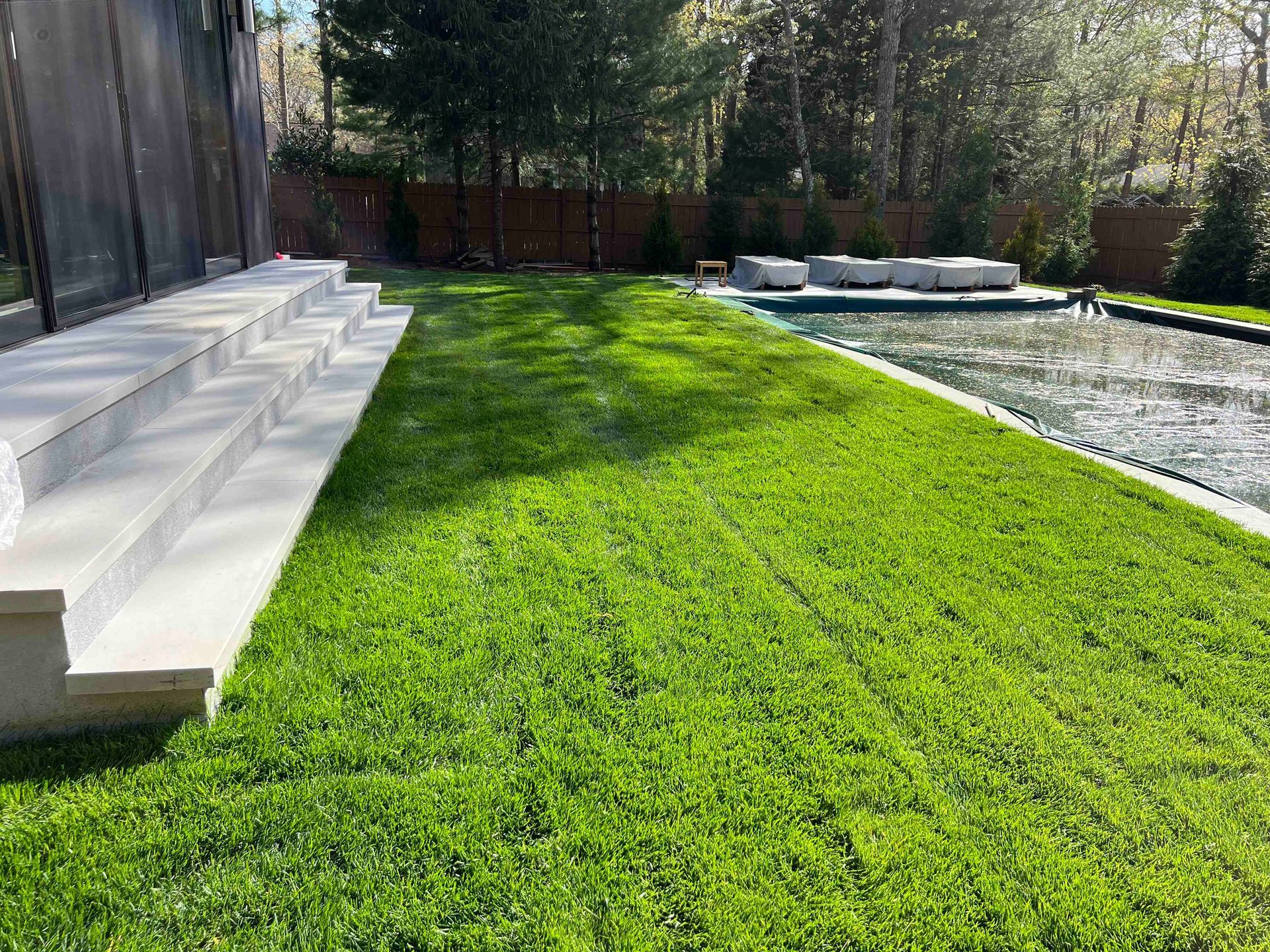 A person is laying on the grass next to a pool.