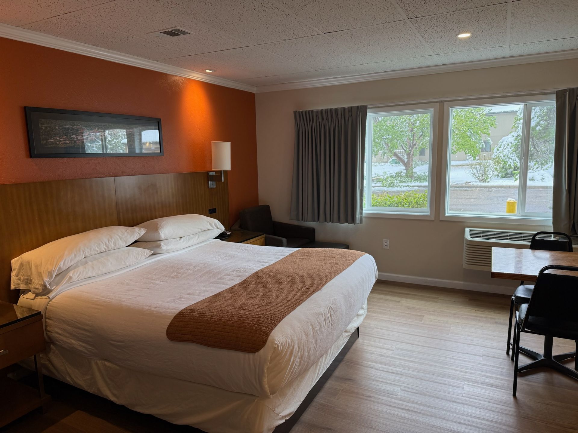 A hotel room with a king size bed , table and chairs.