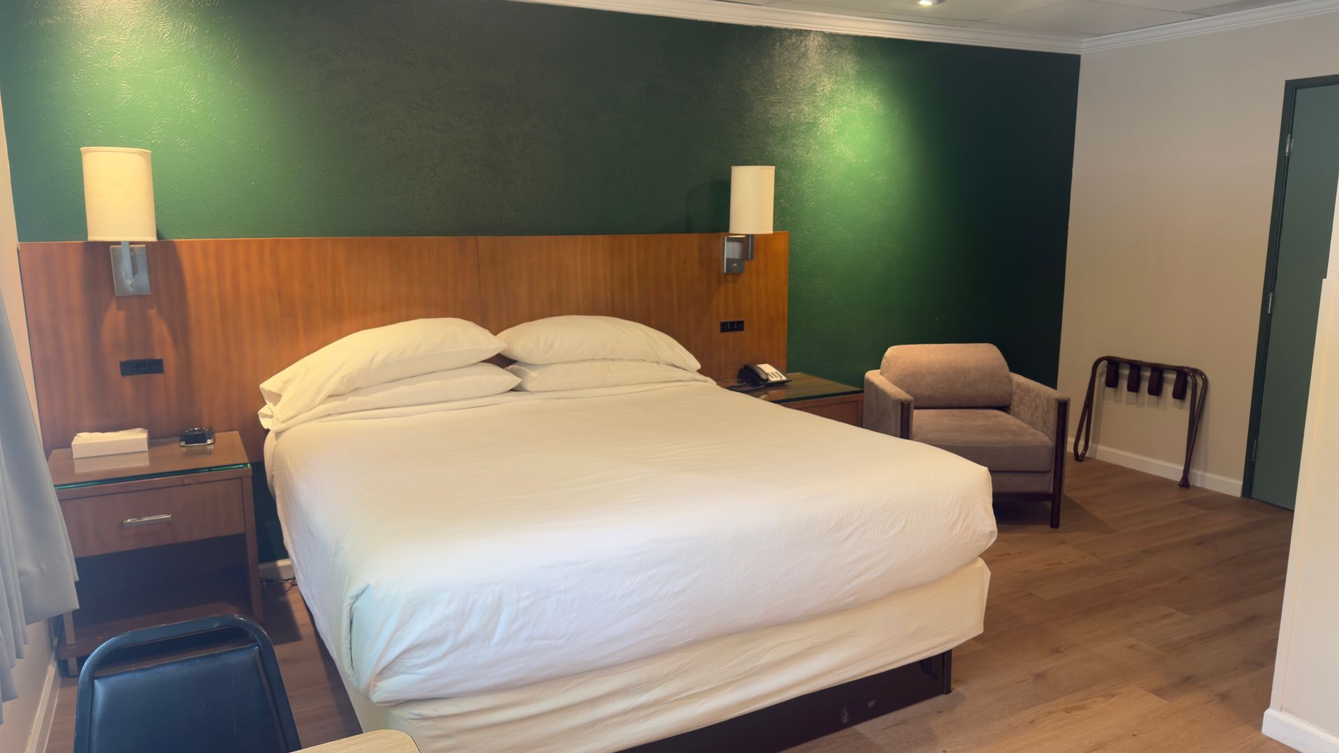 A hotel room with a king size bed and a chair