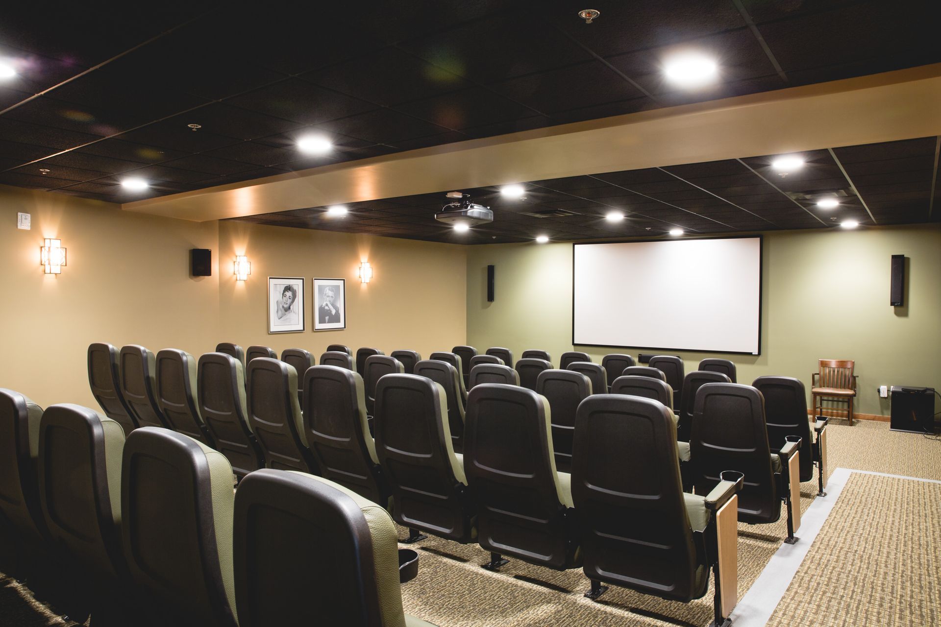 Empty theater seating facing a large projection screen in a warmly lit auditorium