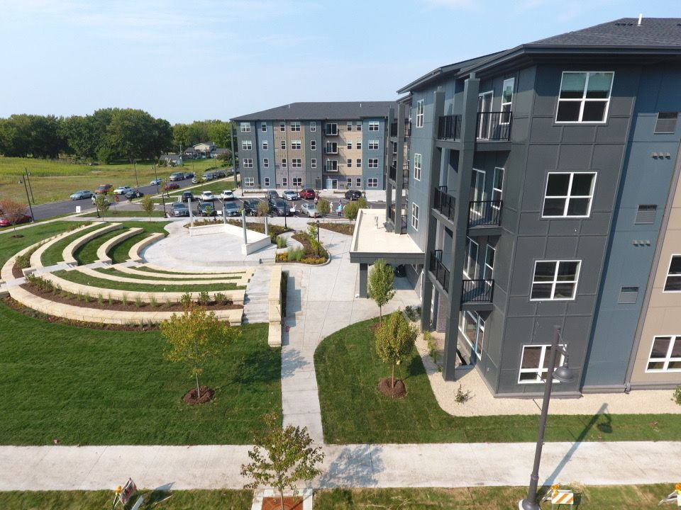 Modern apartment buildings beside a landscaped courtyard with curved stone seating and grass paths