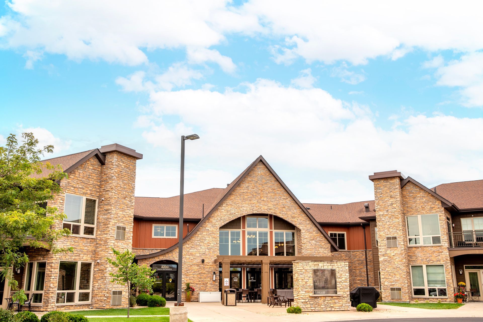 Stone building exterior with arched entrance, large windows, and a partly cloudy blue sky.
