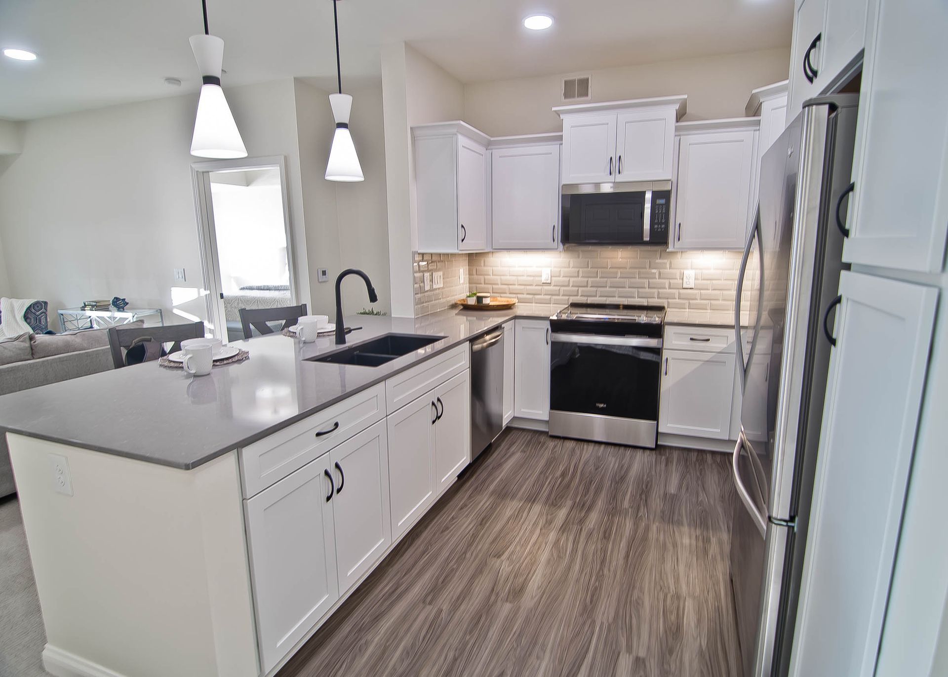 Modern kitchen with white cabinetry, gray countertops, stainless steel appliances, and a central island.
