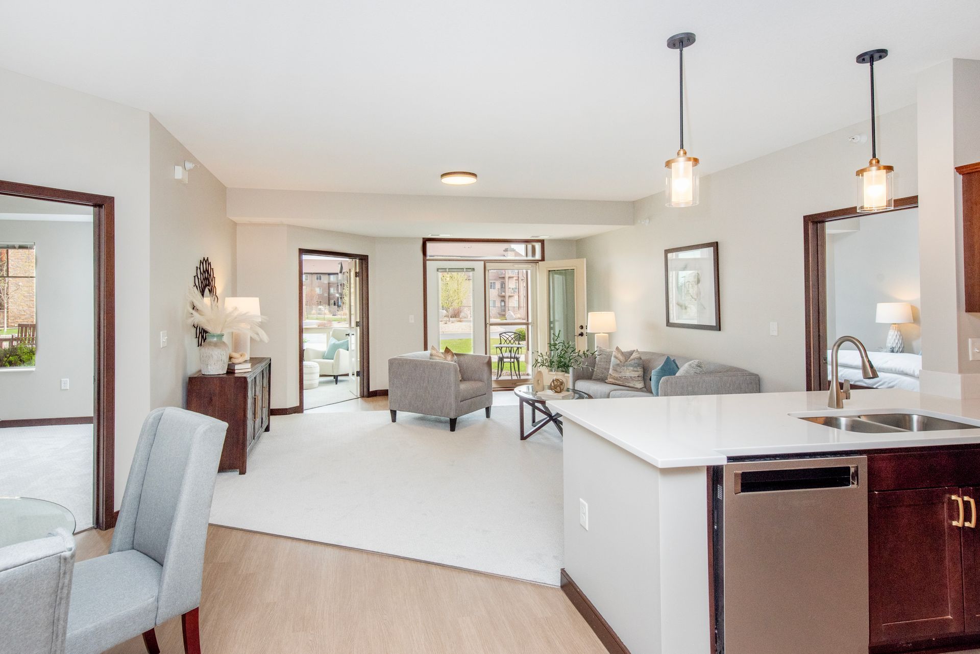 Bright open-plan living room with kitchen island, gray seating, and sliding glass doors.