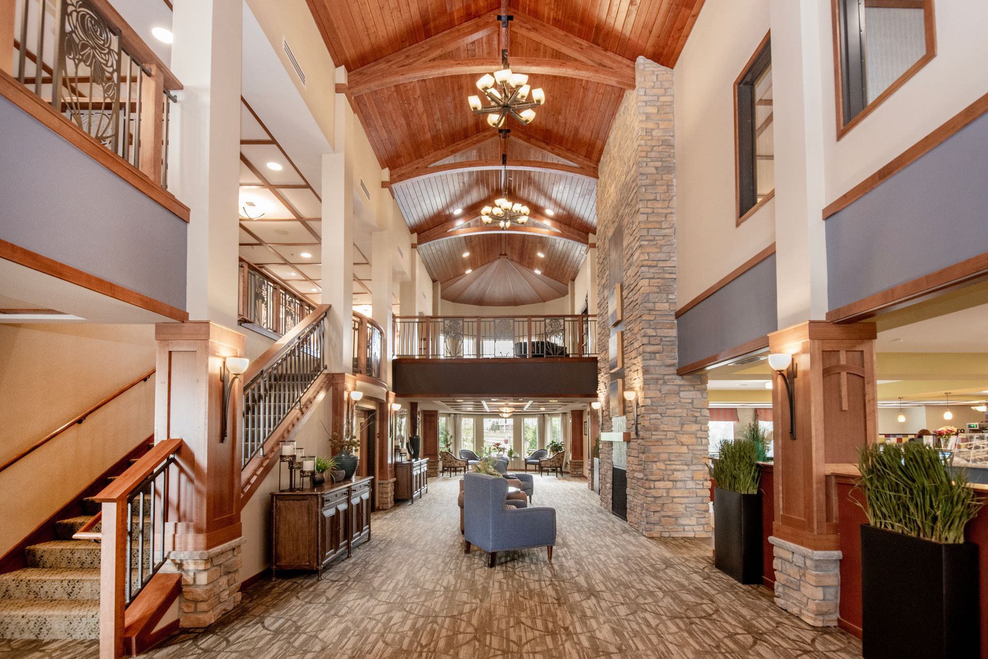 Lodge lobby with high wood ceiling, stone fireplace, stairs, and seating area