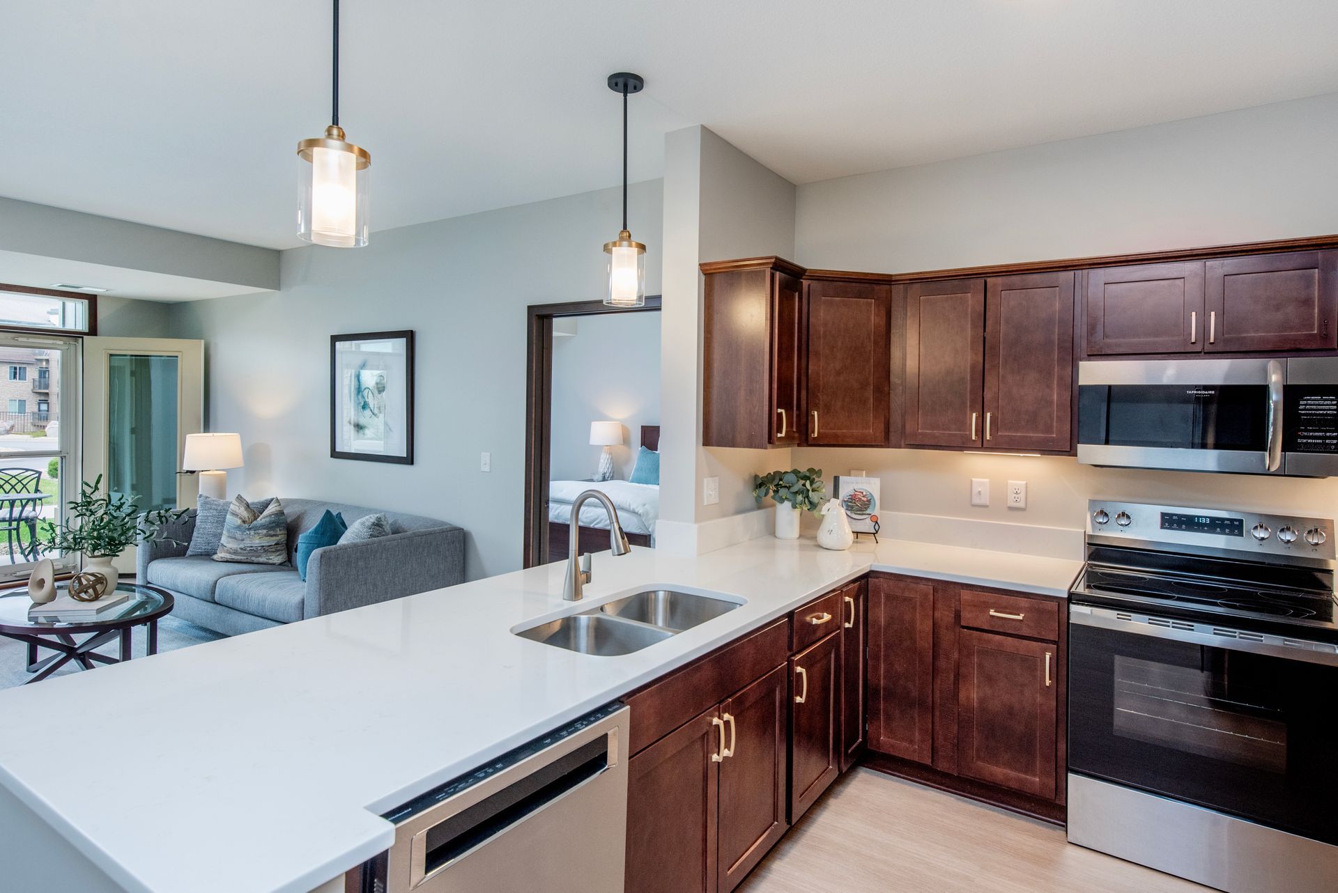 Bright kitchen with dark wood cabinets, white island, and view into a living room with blue seating