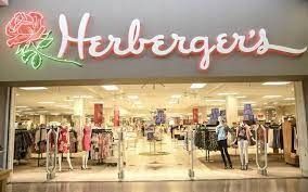 The storefront of a Herberger’s department store with its pink neon sign and rose logo above the entrance.