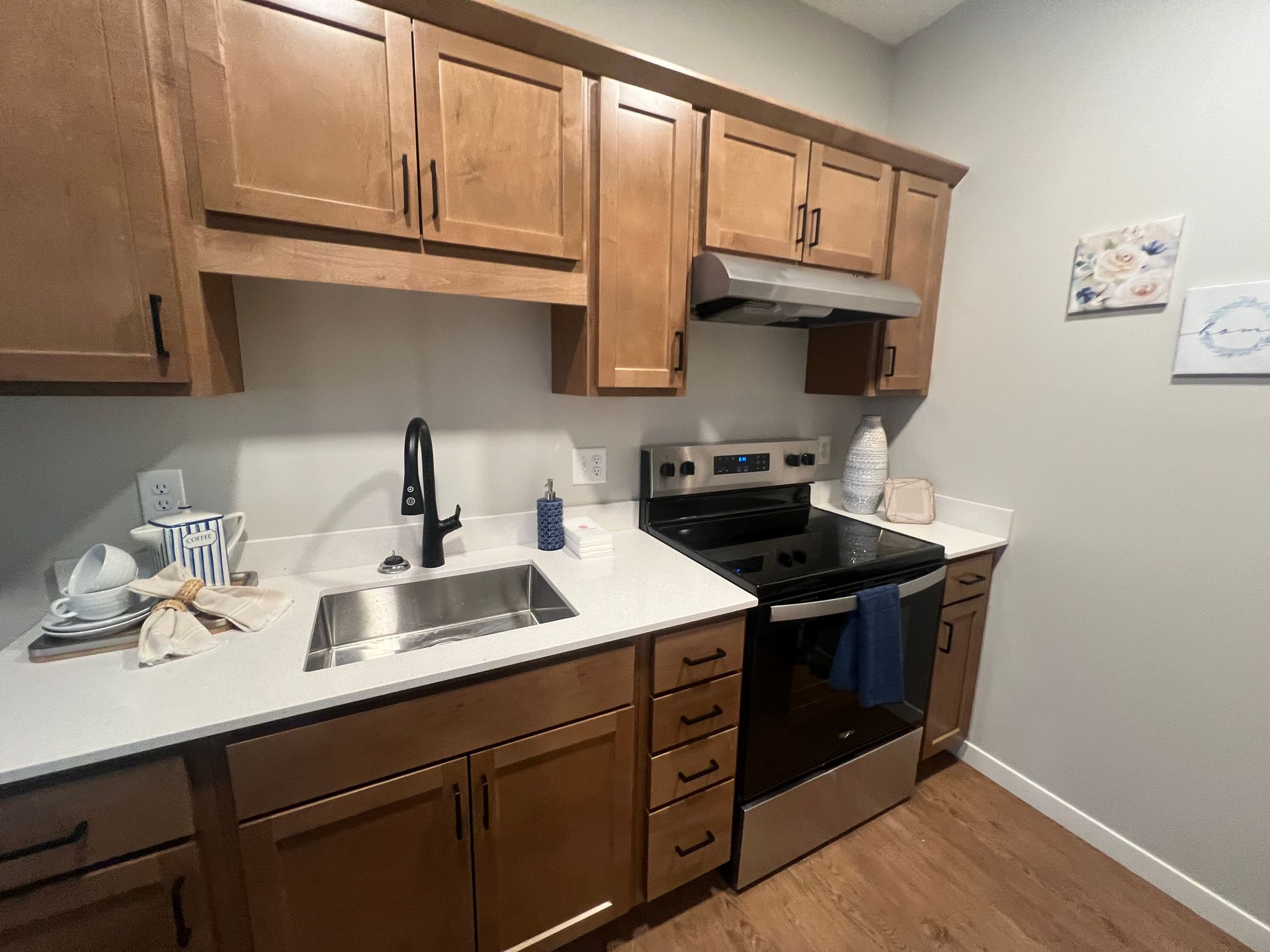 A modern kitchen kitchenette featuring light wood cabinets, stainless steel appliances, and white quartz countertops.