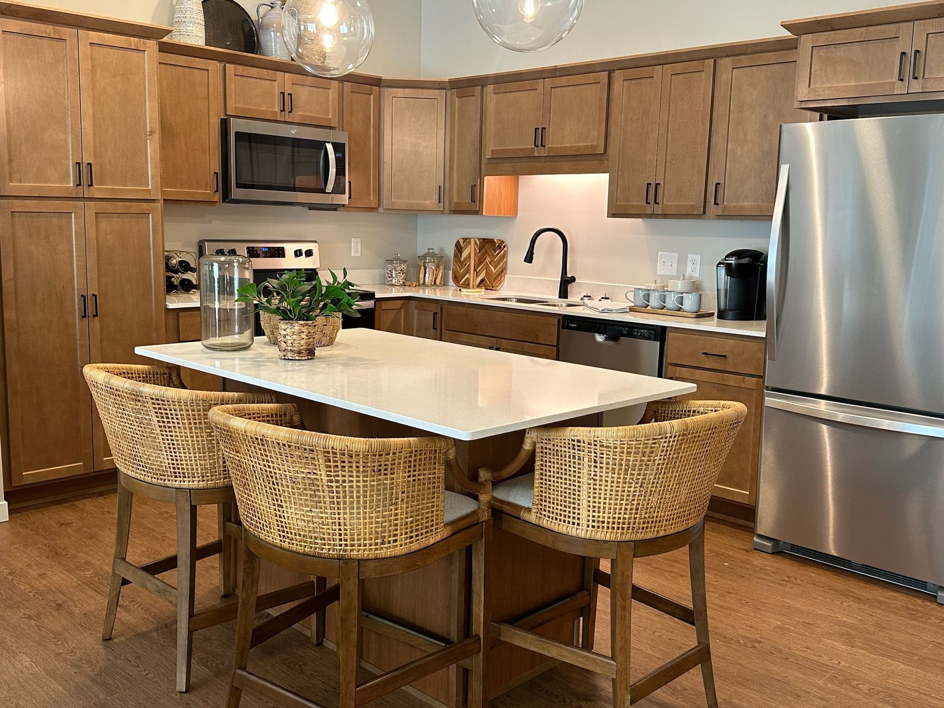 Modern kitchen with wood cabinets, stainless steel appliances, and a central island with woven bar stools.