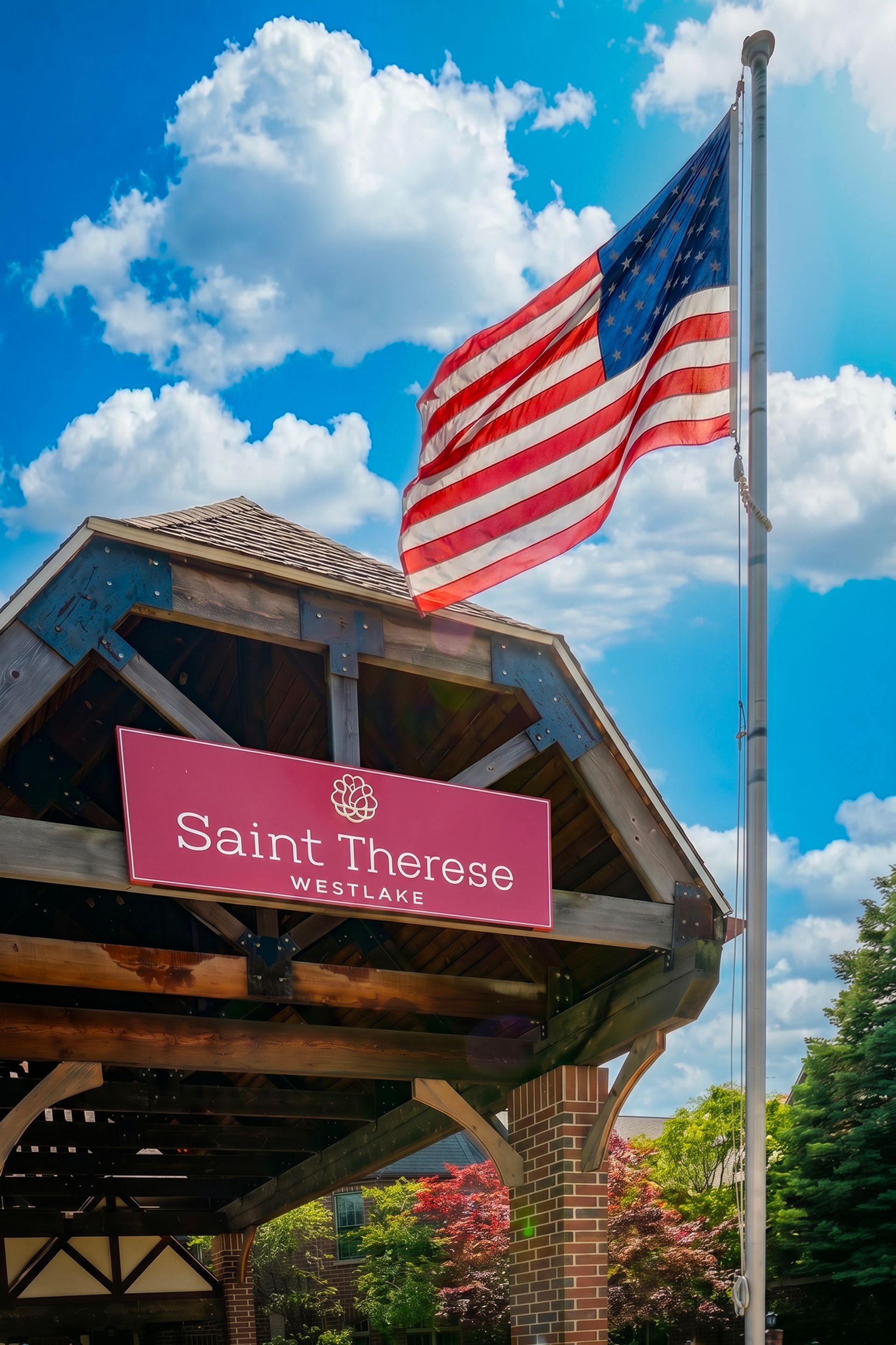 Wooden sign reading “St. Lawrence” beneath a flying American flag against a blue sky