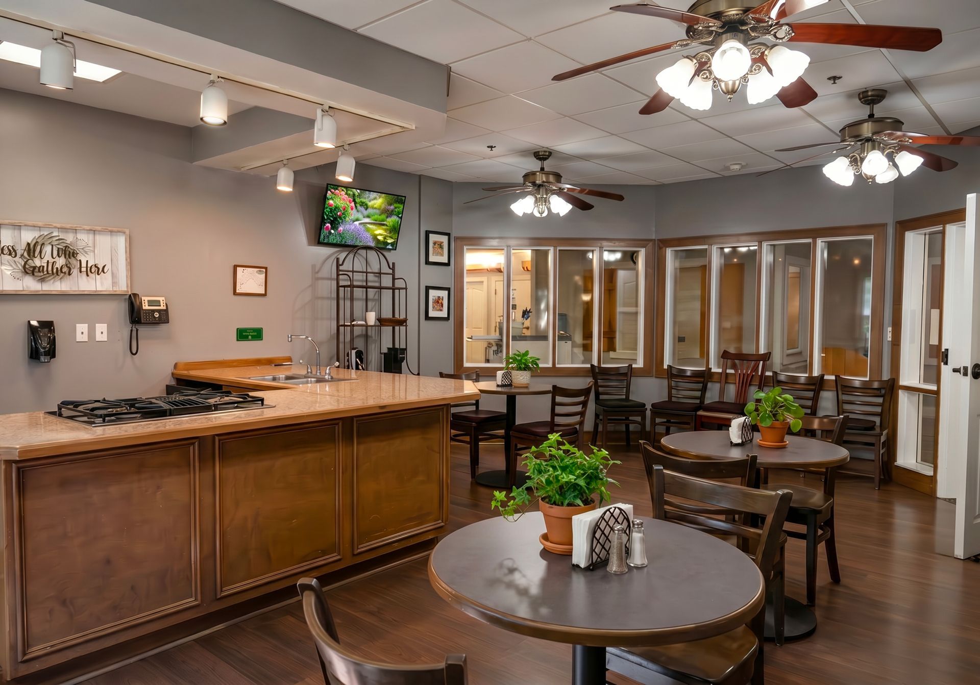 Spacious kitchen showroom with wood cabinets, granite island, ceiling fans, and small dining tables