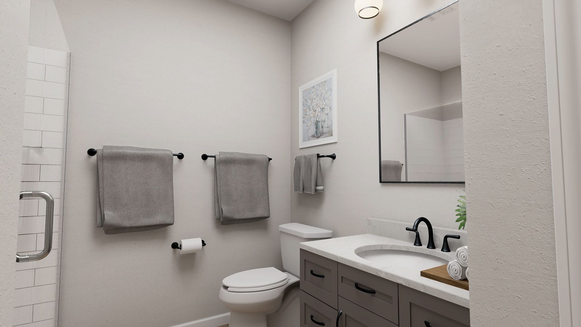 A modern bathroom featuring a grey vanity, a rectangular mirror, a white toilet, and towels hanging on black wall bars.