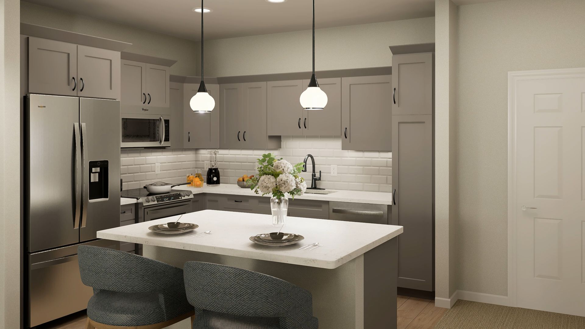 A modern kitchen with grey cabinets, stainless steel appliances, a white quartz island, and two blue upholstered chairs.