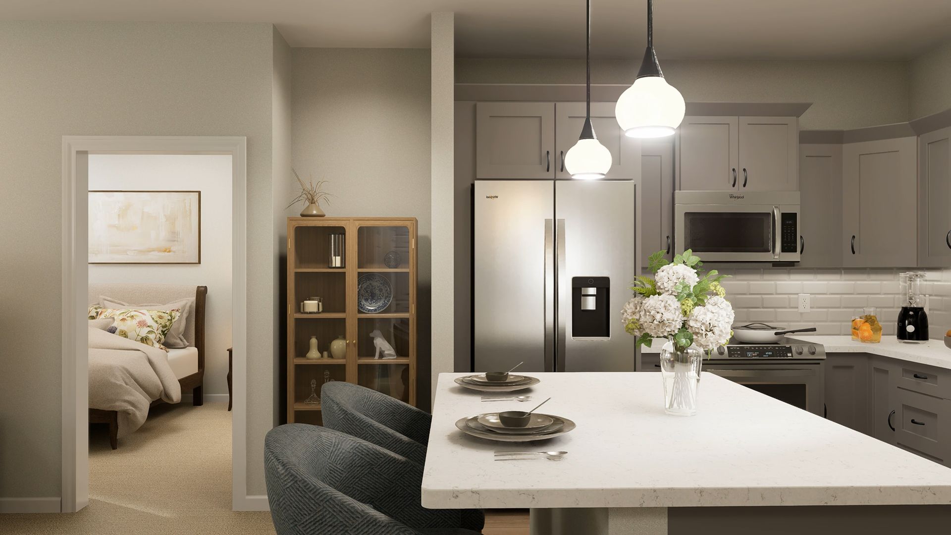 A bright kitchen with a white island and grey cabinets, featuring two pendant lights and a view into a bedroom.