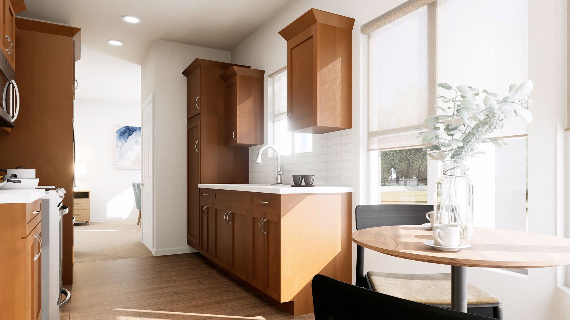 A bright kitchen with wood cabinets, white countertops, and a small dining table with chairs by a window.