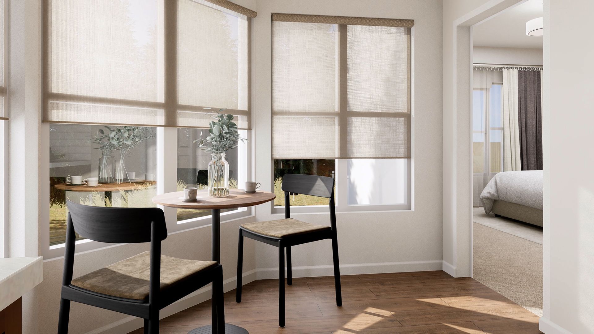 A bright breakfast nook with two black chairs at a round table, positioned next to large windows with light brown shades.