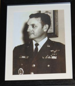 Framed black-and-white portrait of a military officer in uniform, positioned in profile against a light background.