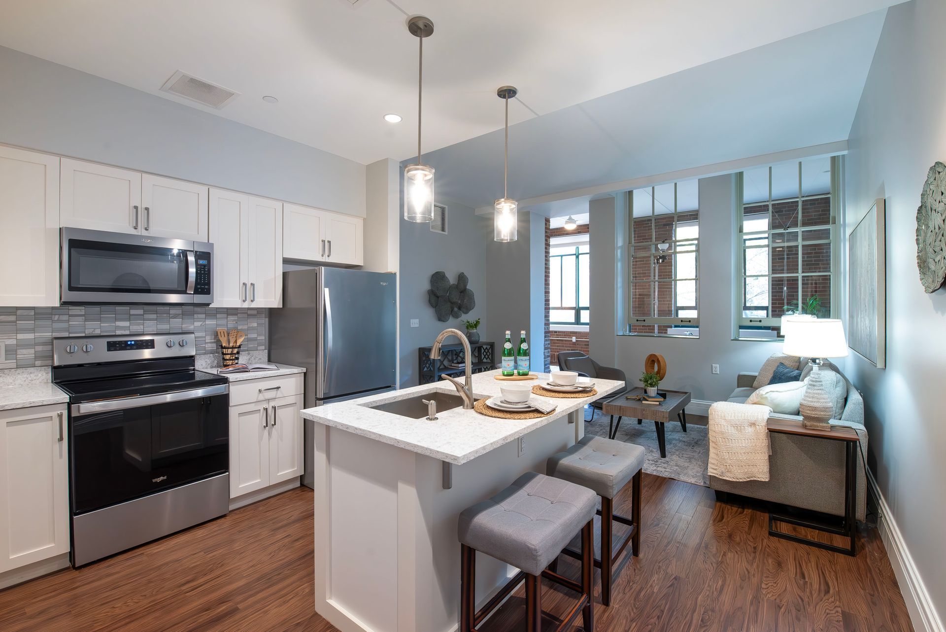 Modern open-concept apartment with white cabinetry, stainless appliances, a kitchen island, and a cozy living area.