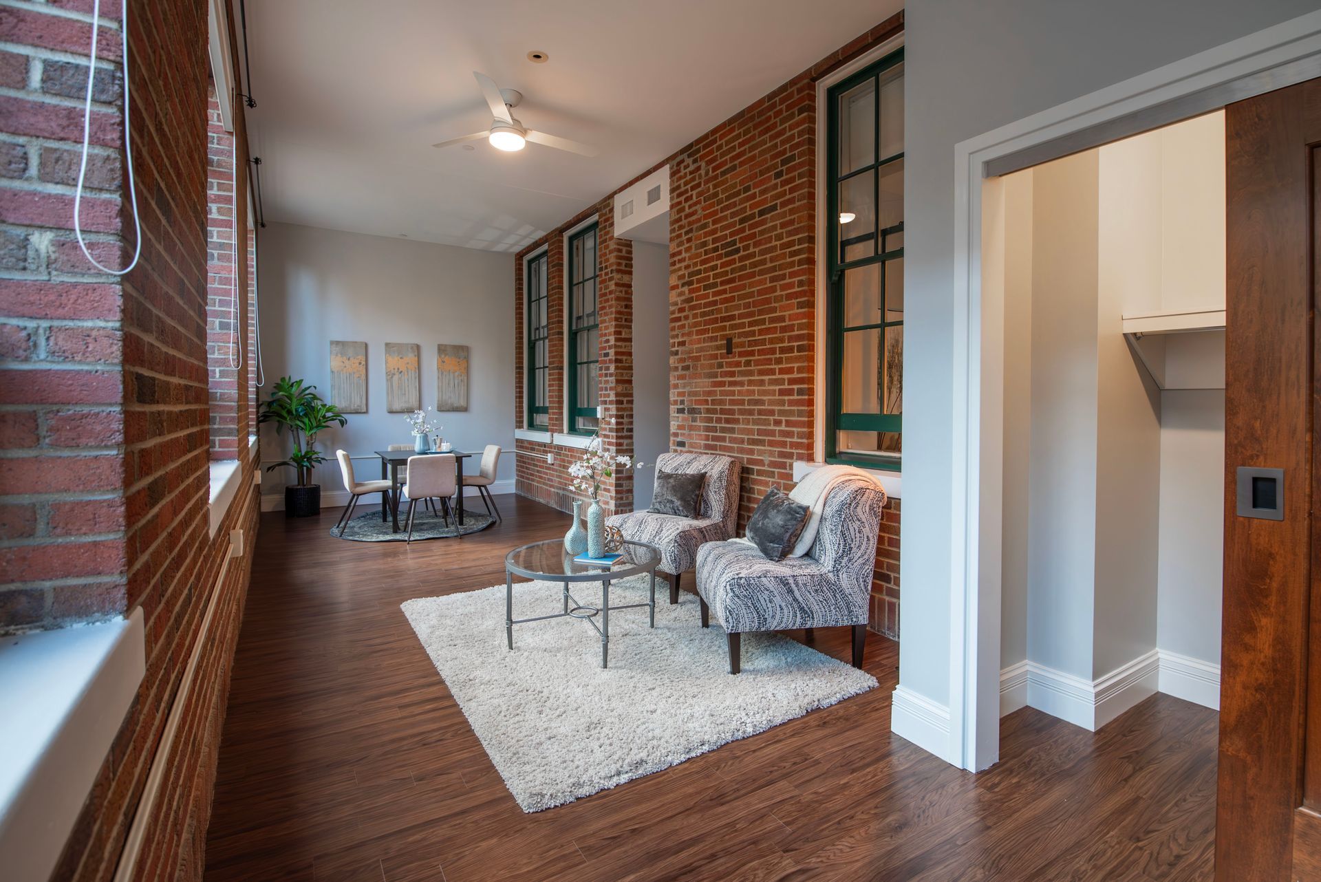 Modern apartment hallway with brick walls, wood floors, and a seating area on a white rug