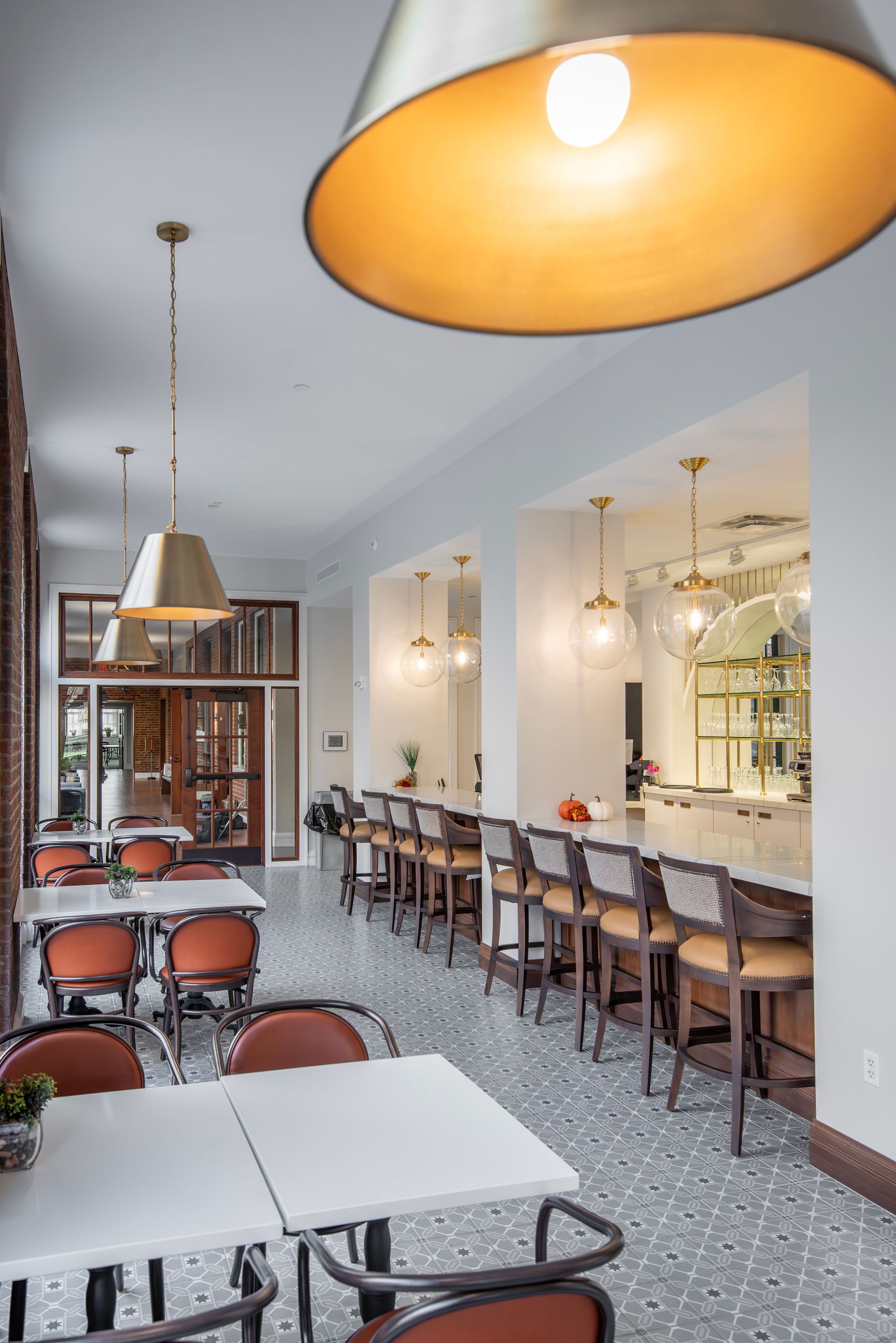 Bright café interior with long communal tables, pendant lights, and a patterned tile floor