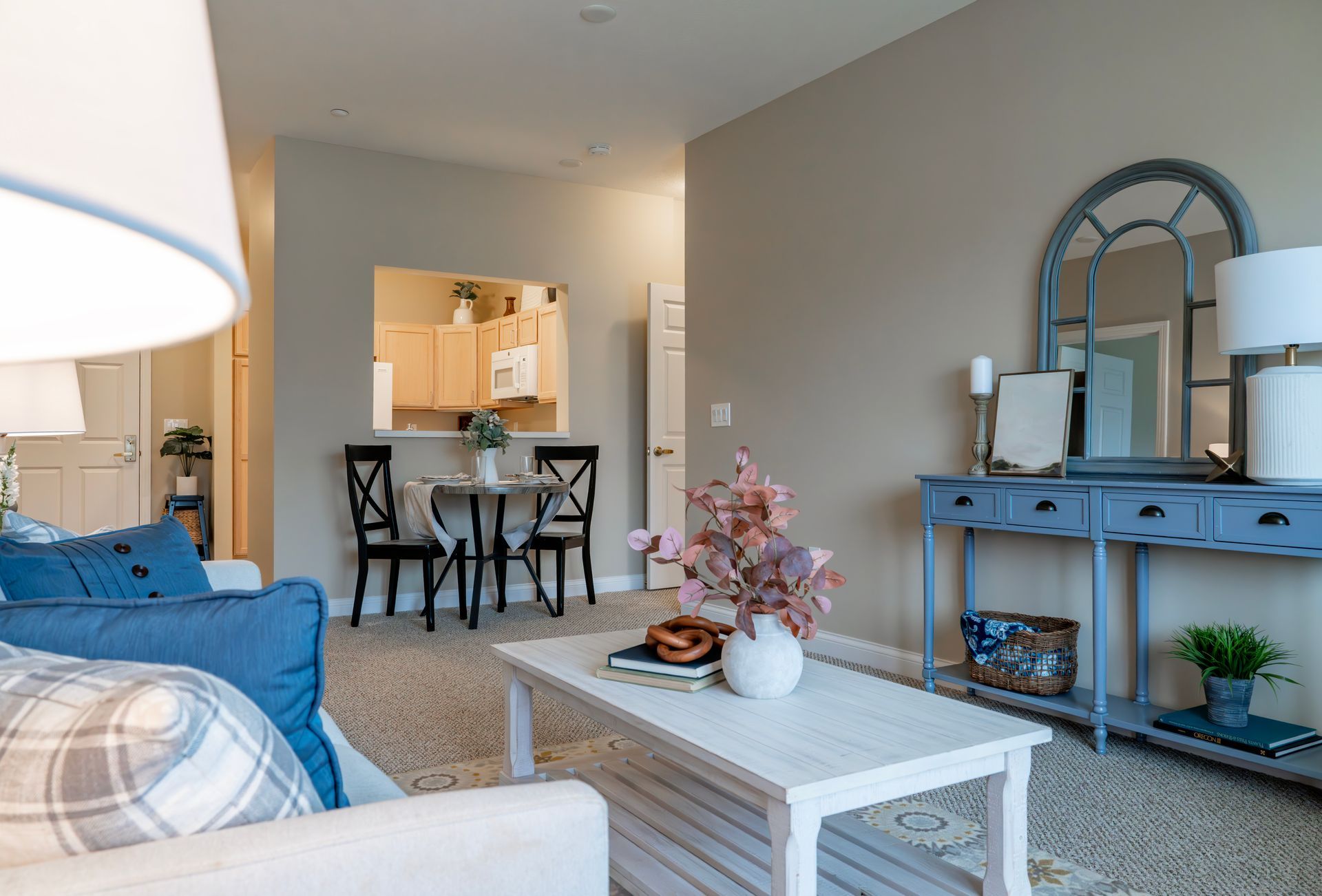 Bright living room with blue sofa, white coffee table, blue console, and dining area beyond