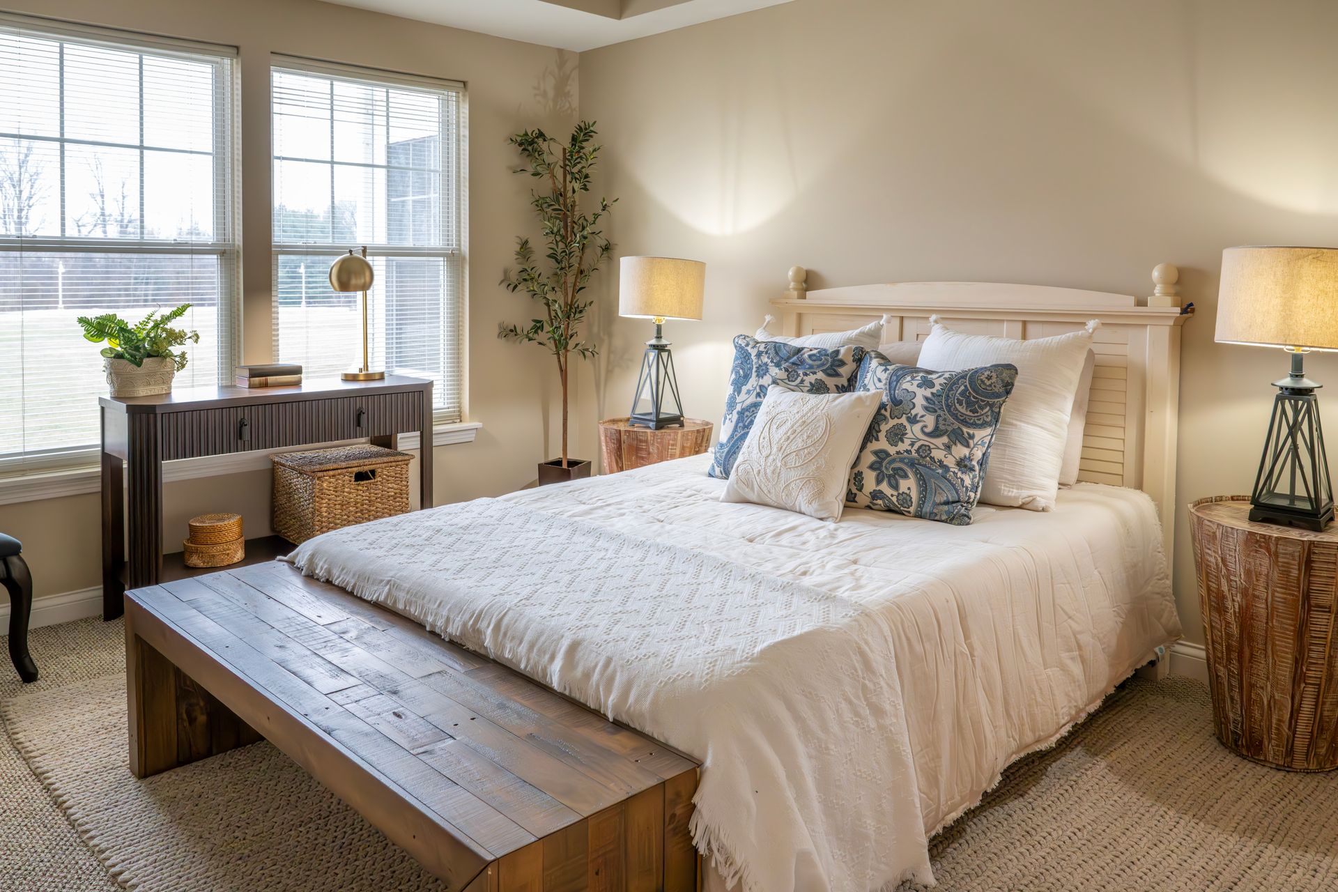 Cozy bedroom with a wooden bed, white bedding, bedside lamps, and a sunlit window seat
