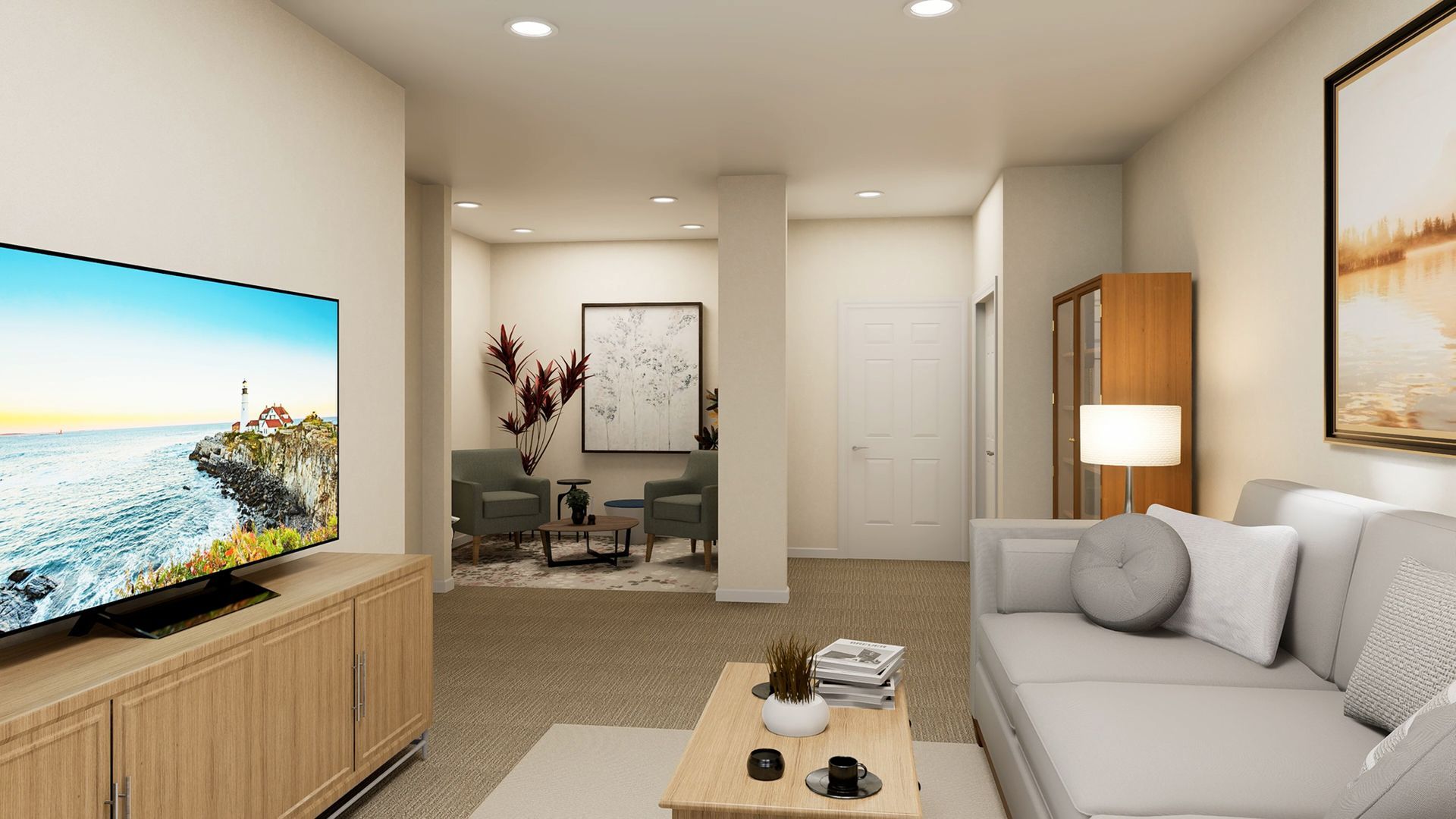 A living room with a TV, a light gray sofa, and a separate seating area with two chairs and wall art.