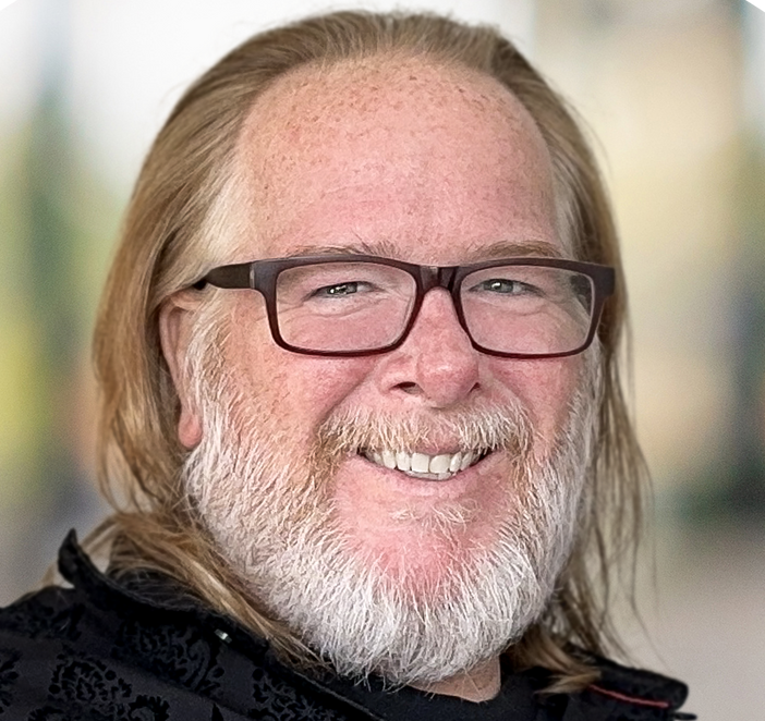 A man with glasses and a beard is smiling for the camera.