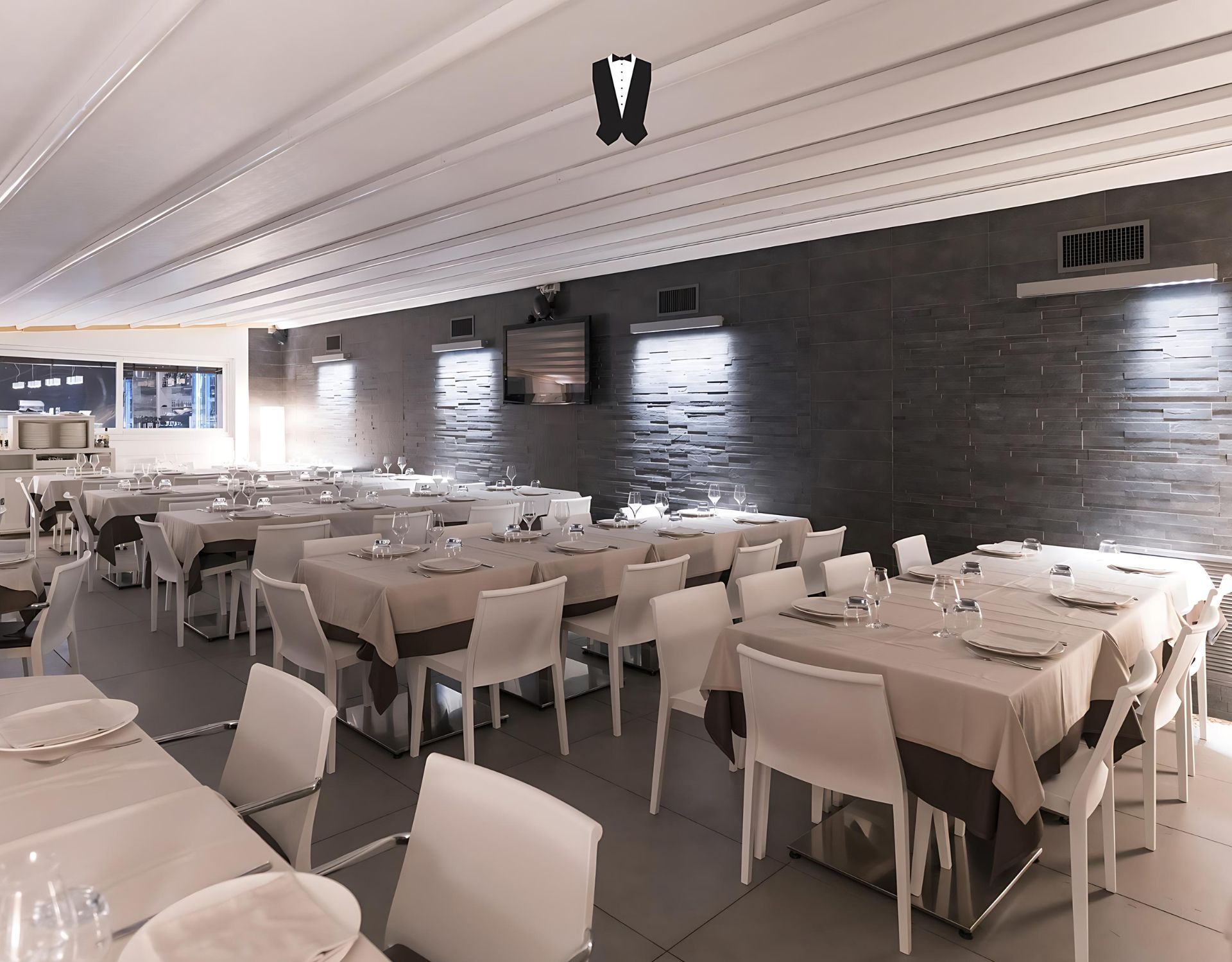 Un'ampia sala da pranzo con tavoli e sedie e tv a parete