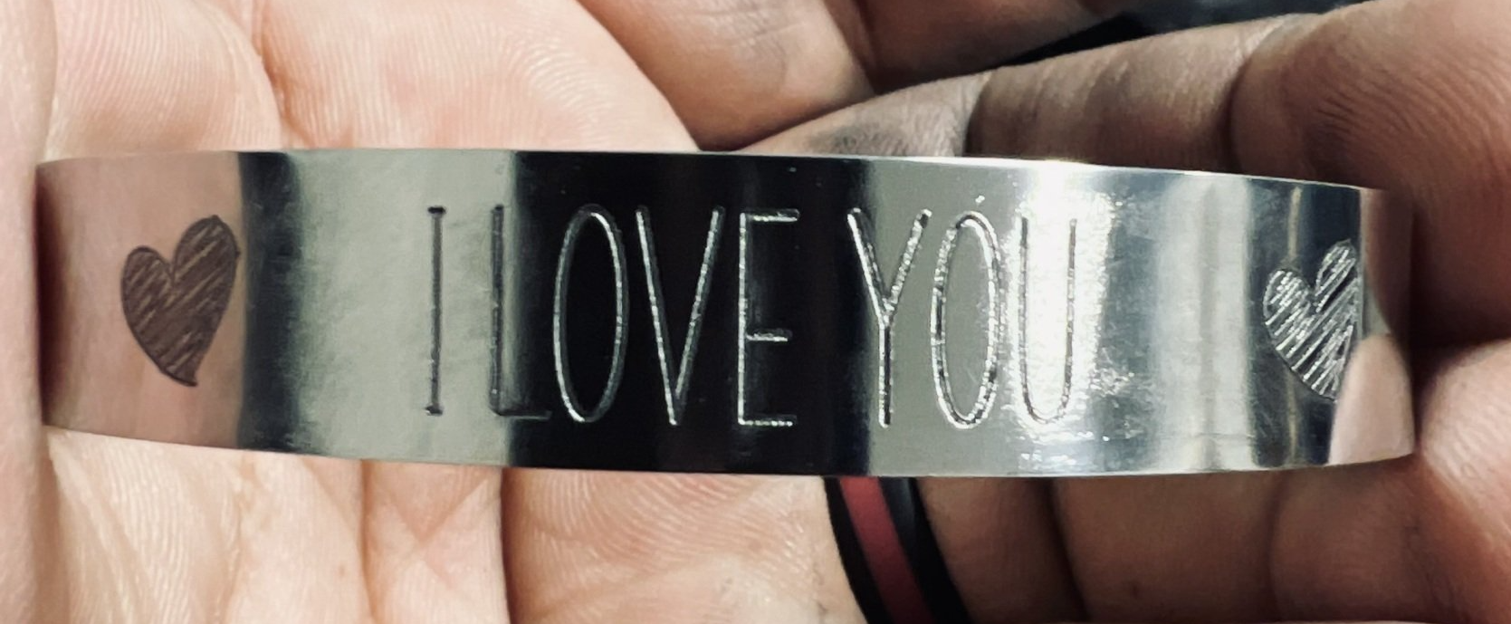 Silver ring engraved “I LOVE YOU” with a small heart design on a hand