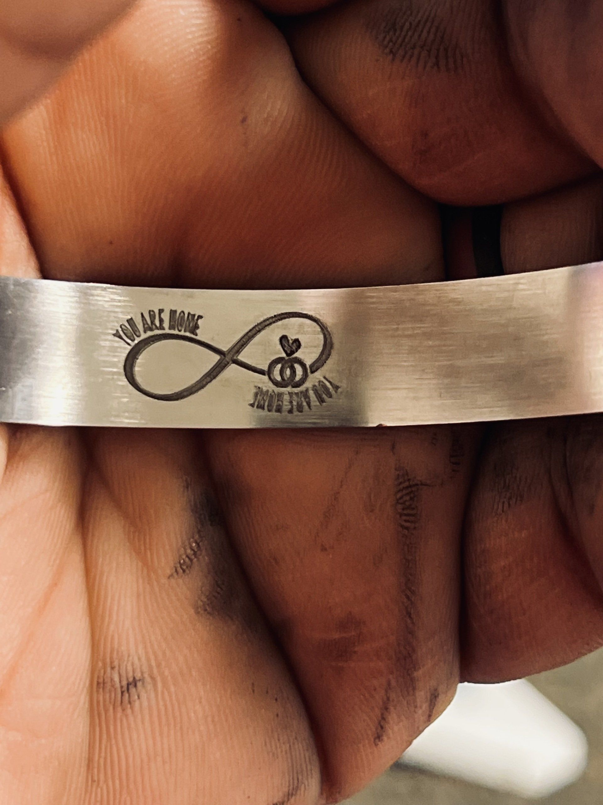 Close-up of a hand holding a small white ribbon with a black infinity symbol and text.