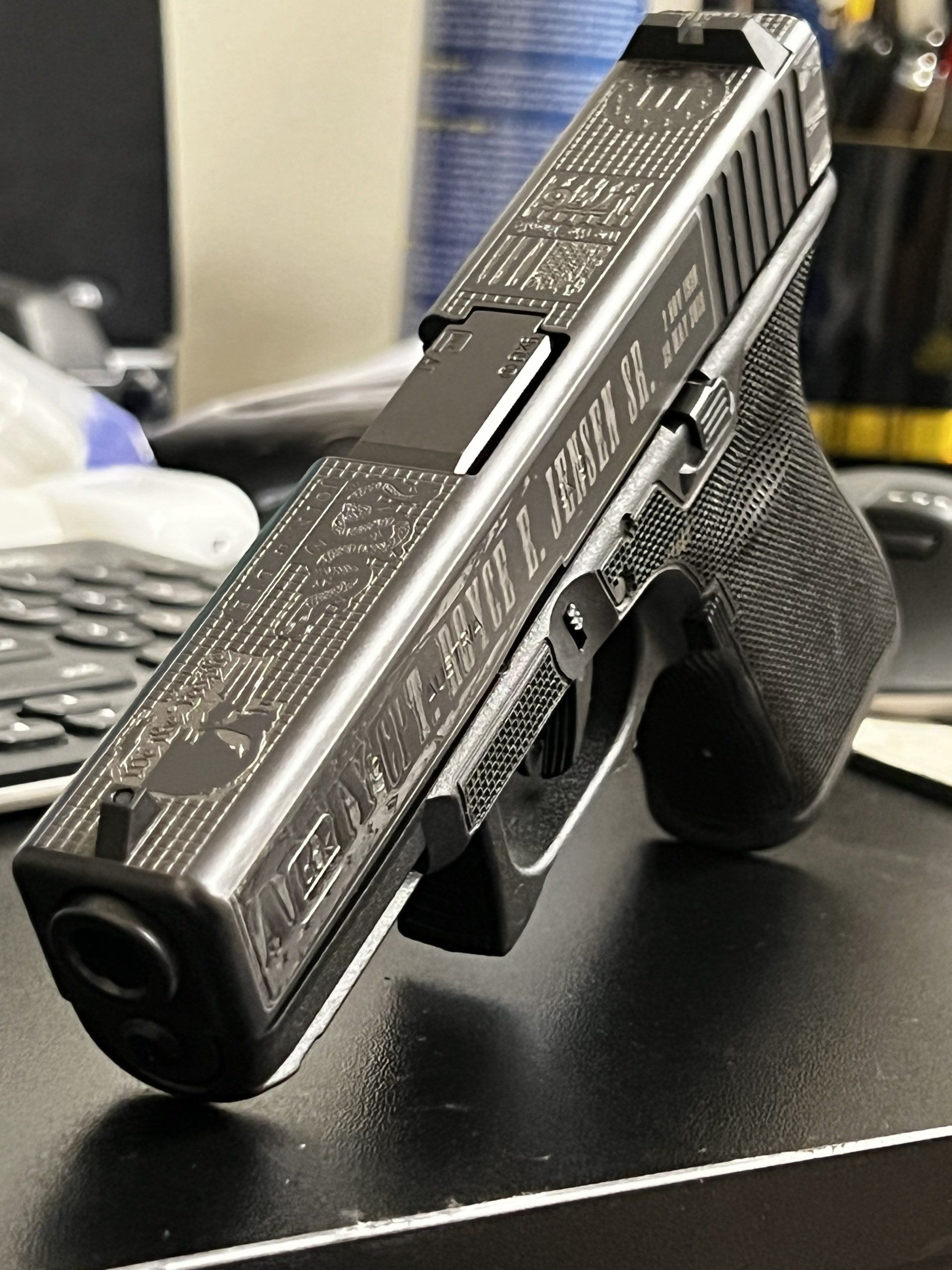 Black handgun with textured grip resting on a desk near a keyboard.
