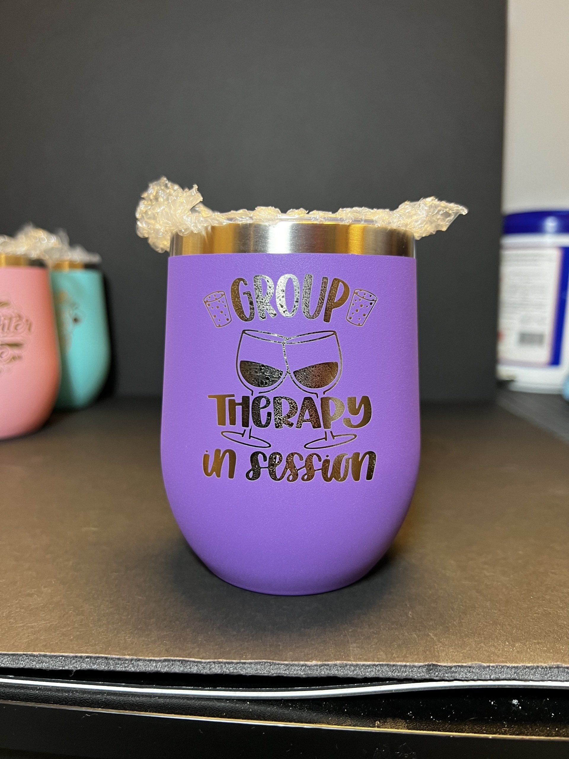 Purple cup with gold glitter rim and “therapy in session” text on a shelf