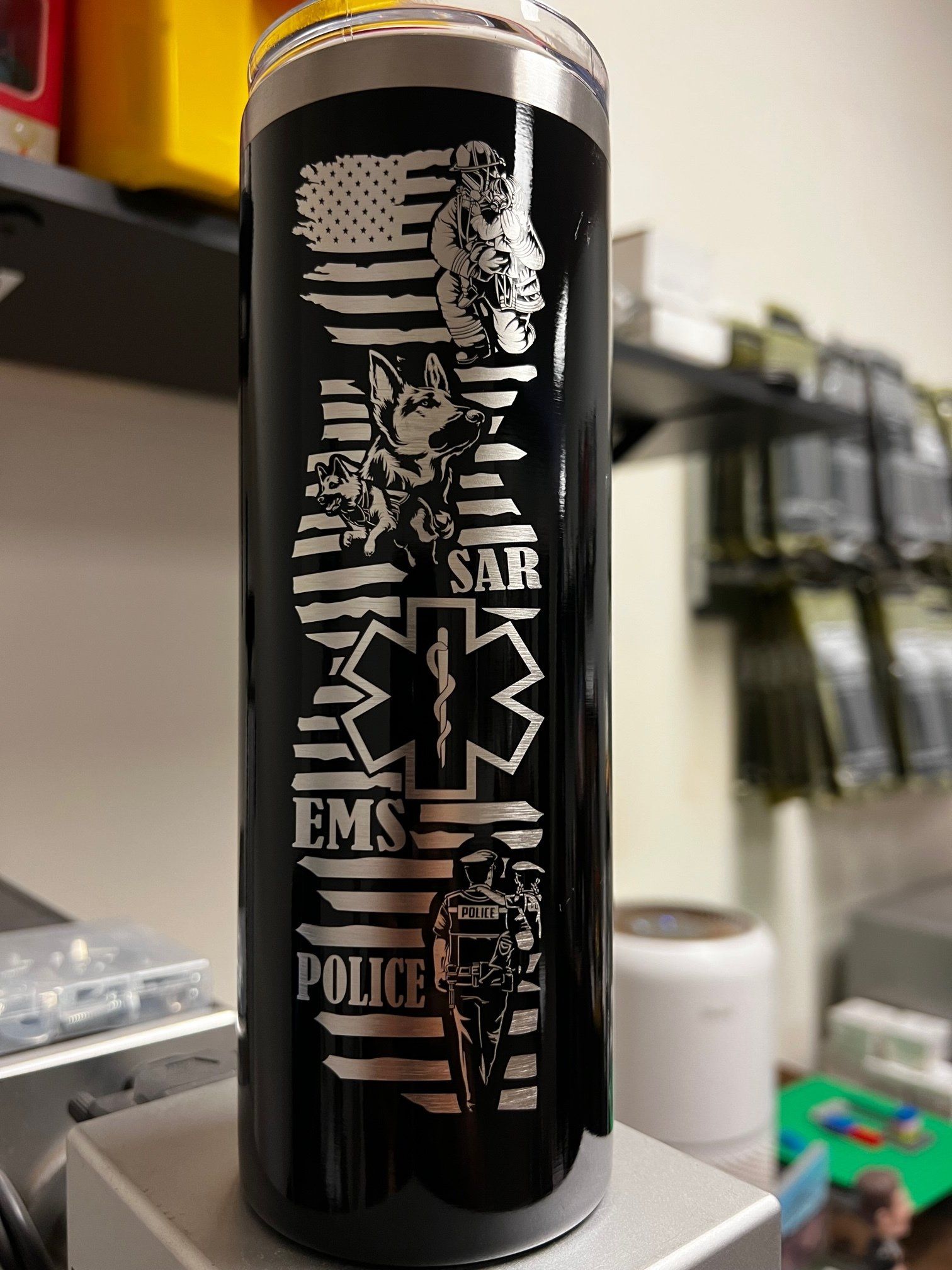 Black tumbler with silver EMS and police symbols on a shelf