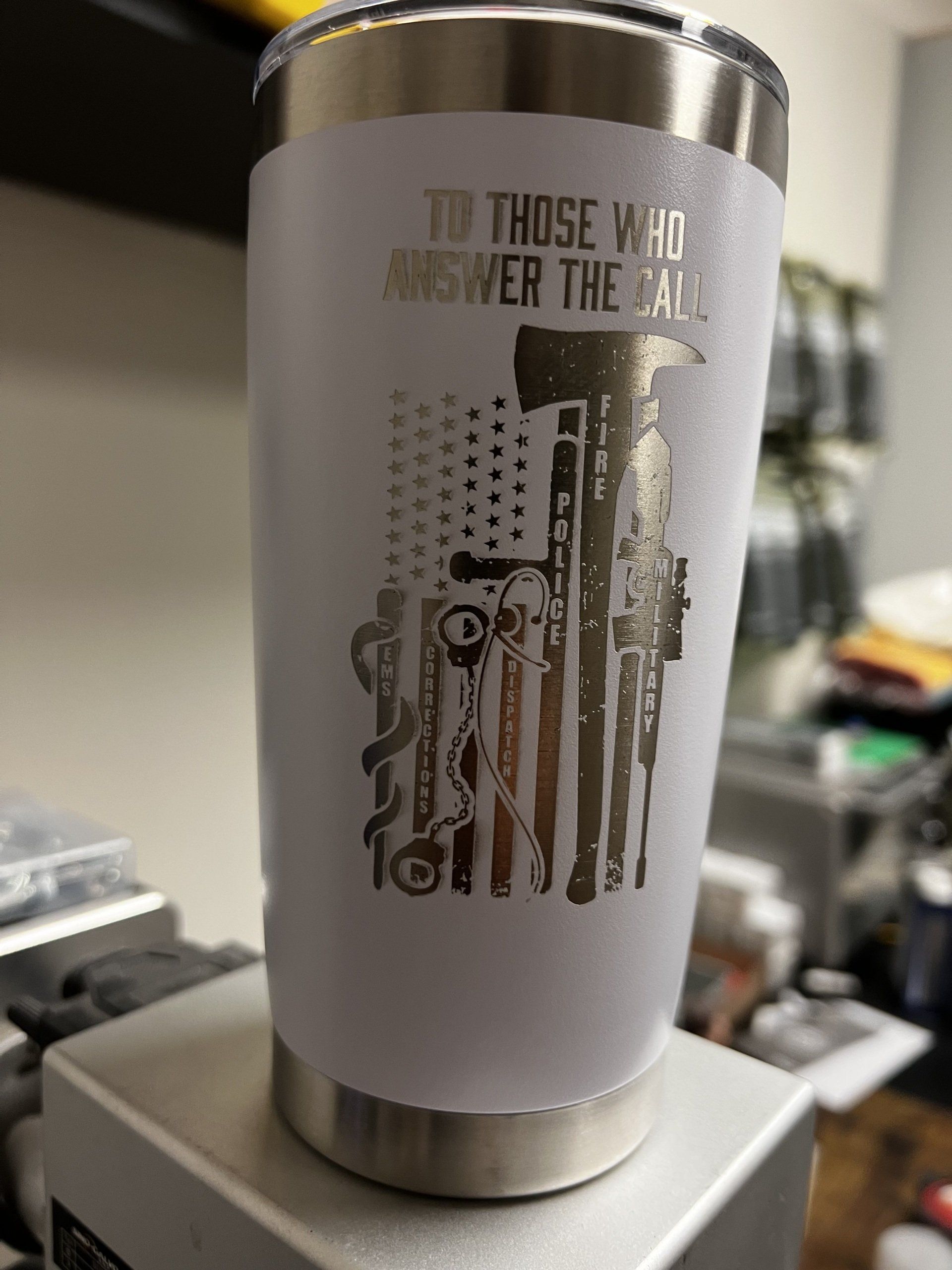 White tumbler with a U.S. flag and firearms graphic on a countertop, with “To those who answer the call” text.