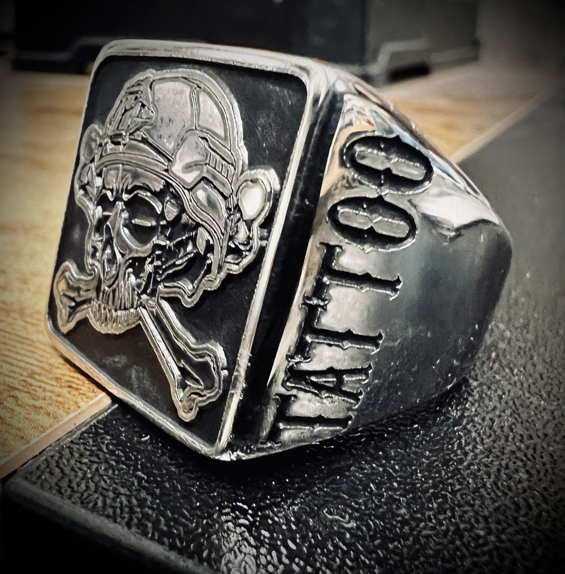 Silver ring with a skull and crossbones design on the front face, and 