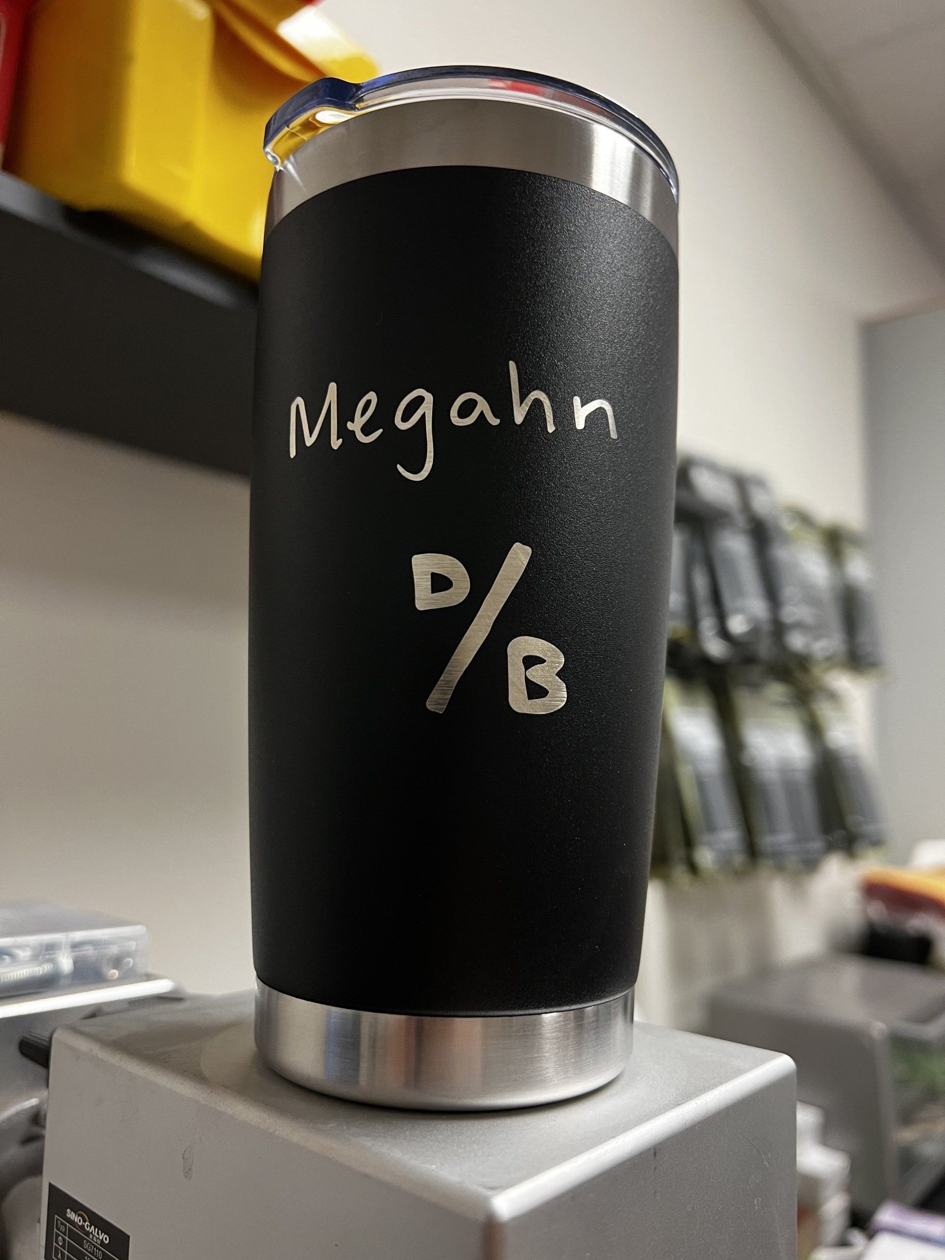 Black insulated tumbler labeled “Megahn” with “D/B” on a counter