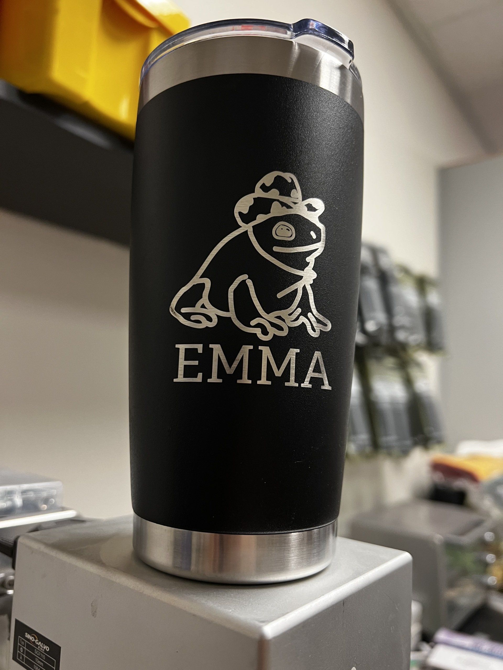 Black tumbler with a white cartoon gorilla and the name “EMMA” engraved on it.