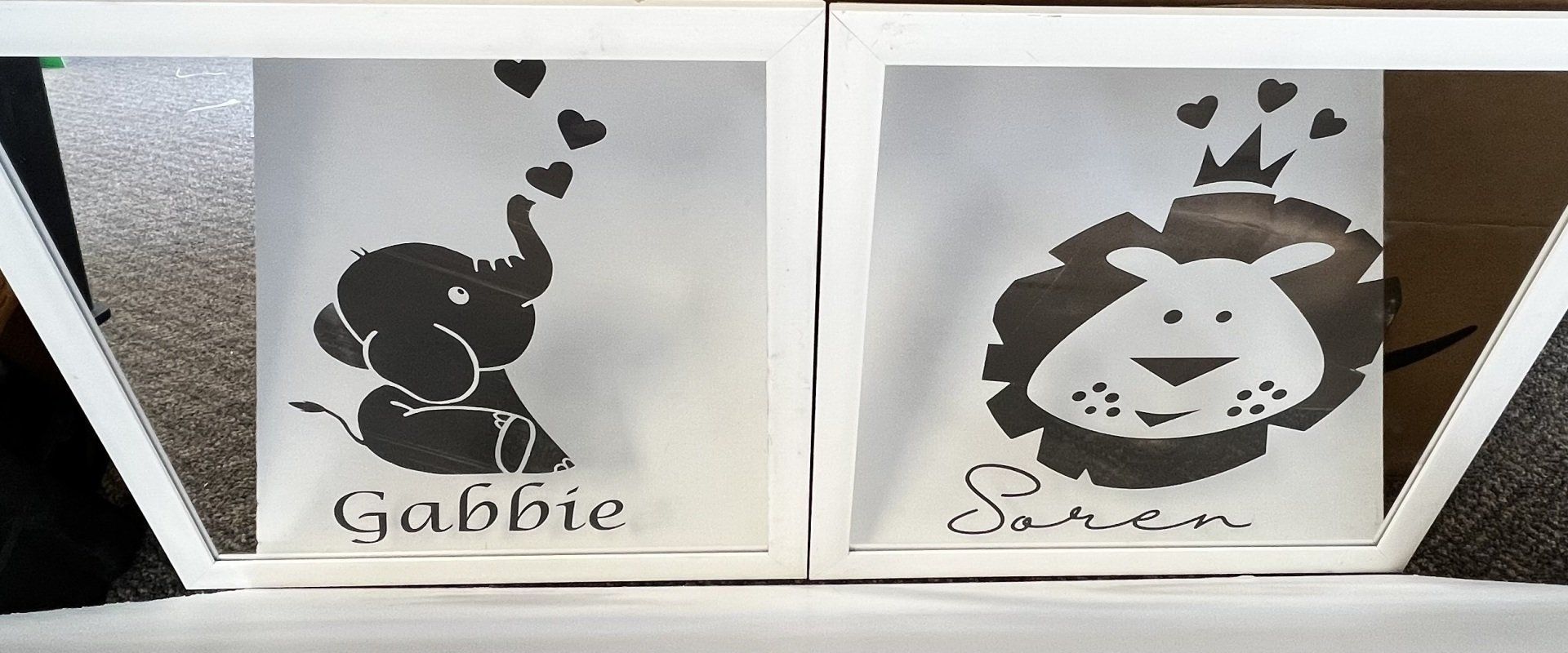 Two black-and-white printed graphics on a wall, each featuring stylized cartoon figures and text.