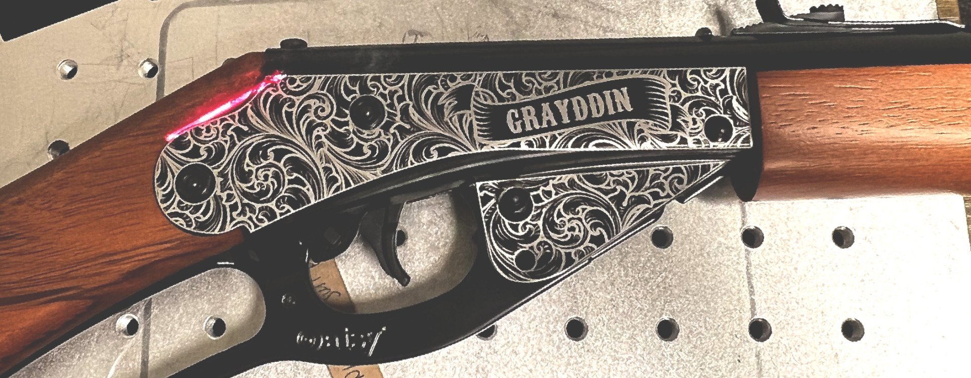 Decorative engraved shotgun with wooden stock on a pegboard background