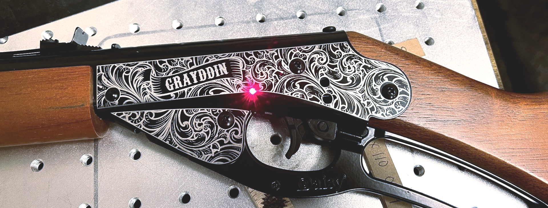 A laser engraves decorative patterns and the word 