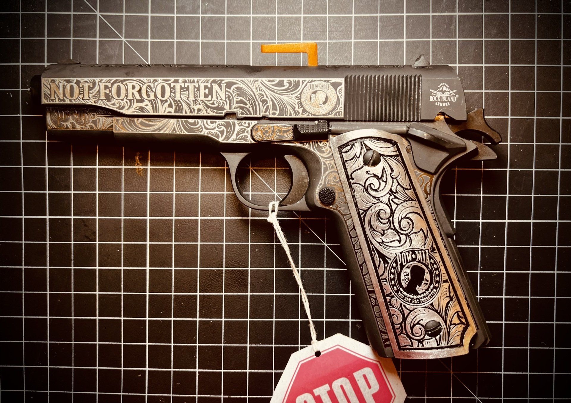 Decorative handgun on a tiled wall, with a red stop tag hanging below.