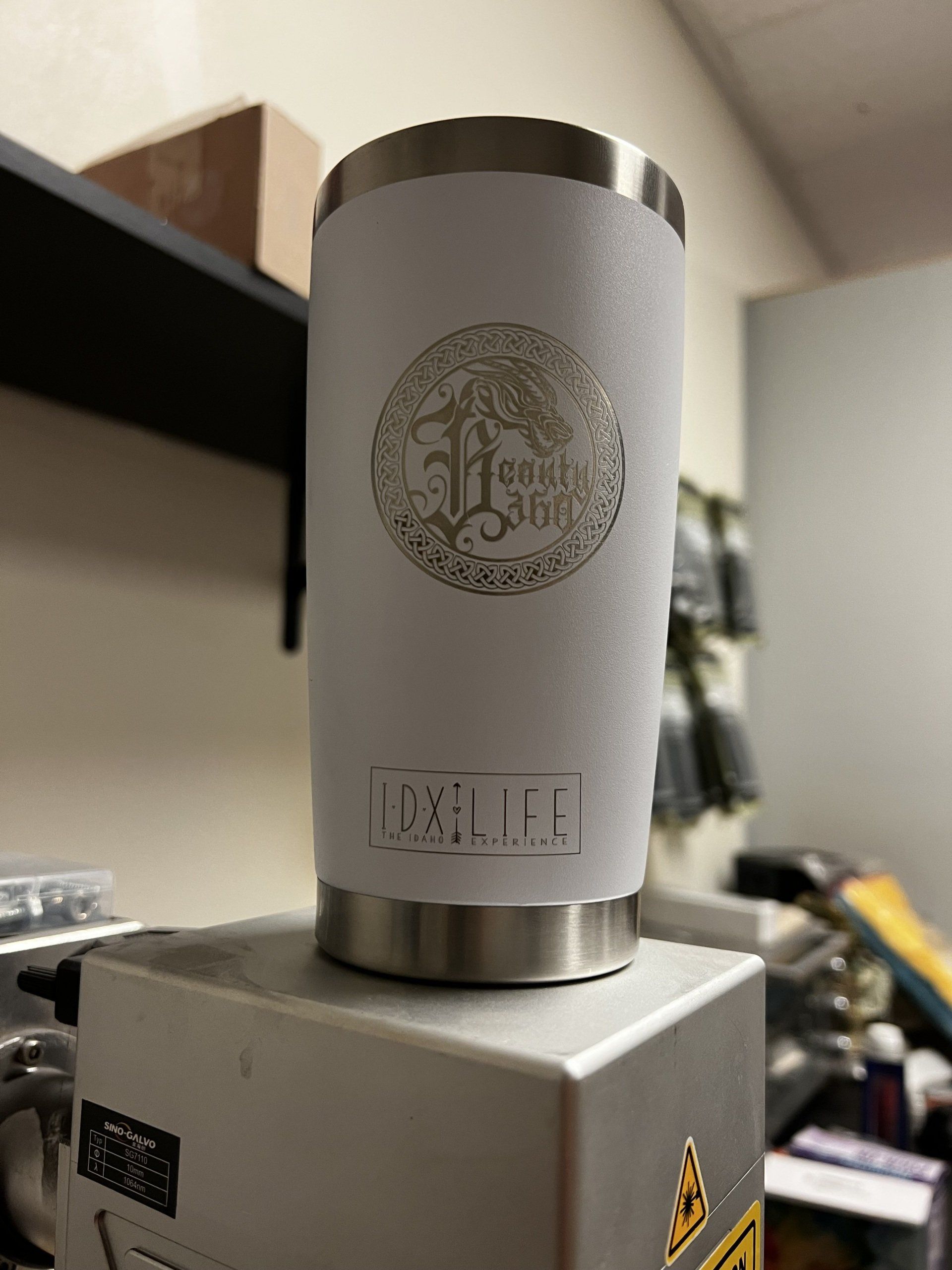 Silver cylindrical device with a circular emblem, mounted on a metal base in an office setting