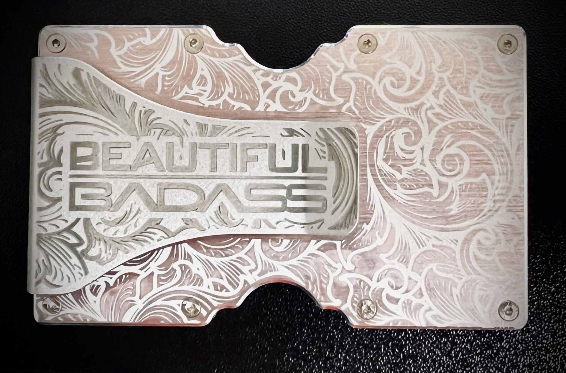 Etched metal plate with floral pattern and “BEAUTIFUL BADASS” text, mounted on a dark surface