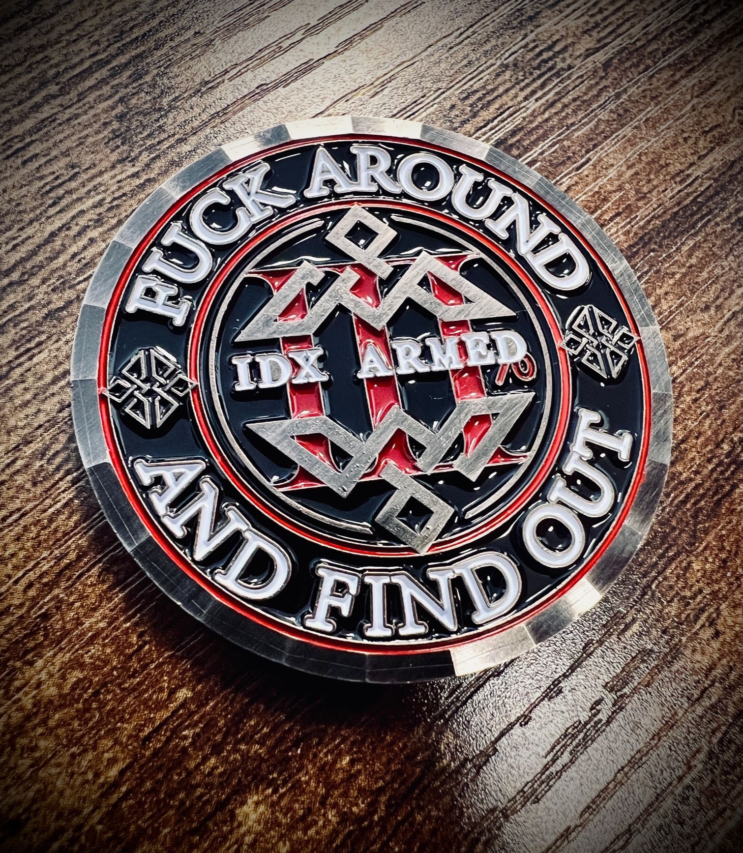 Round metal patch with red, white, and black lettering on a dark wood surface.