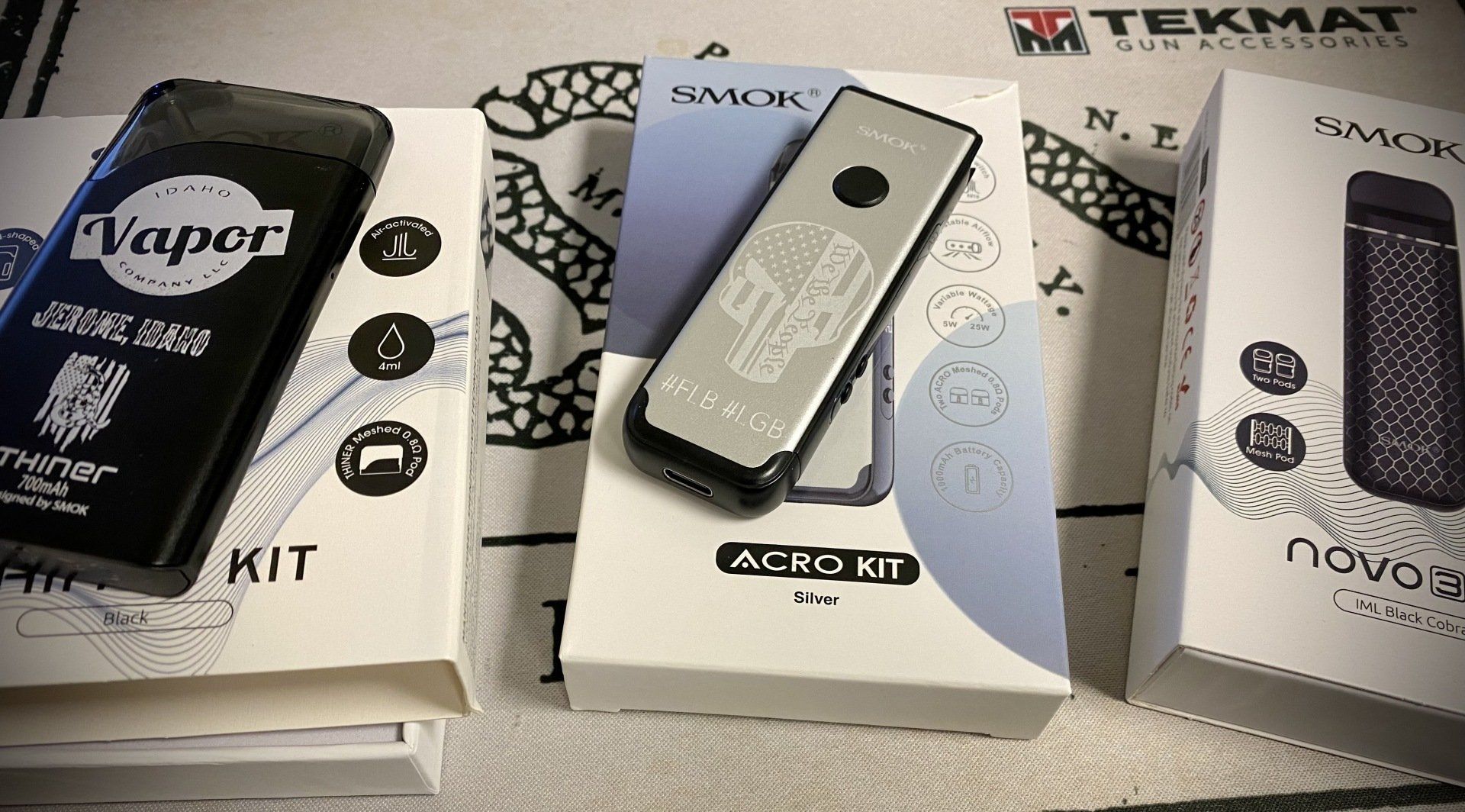 Three vape kits in boxes: Smok Acro Kit, Vapor, and Novo 2X.