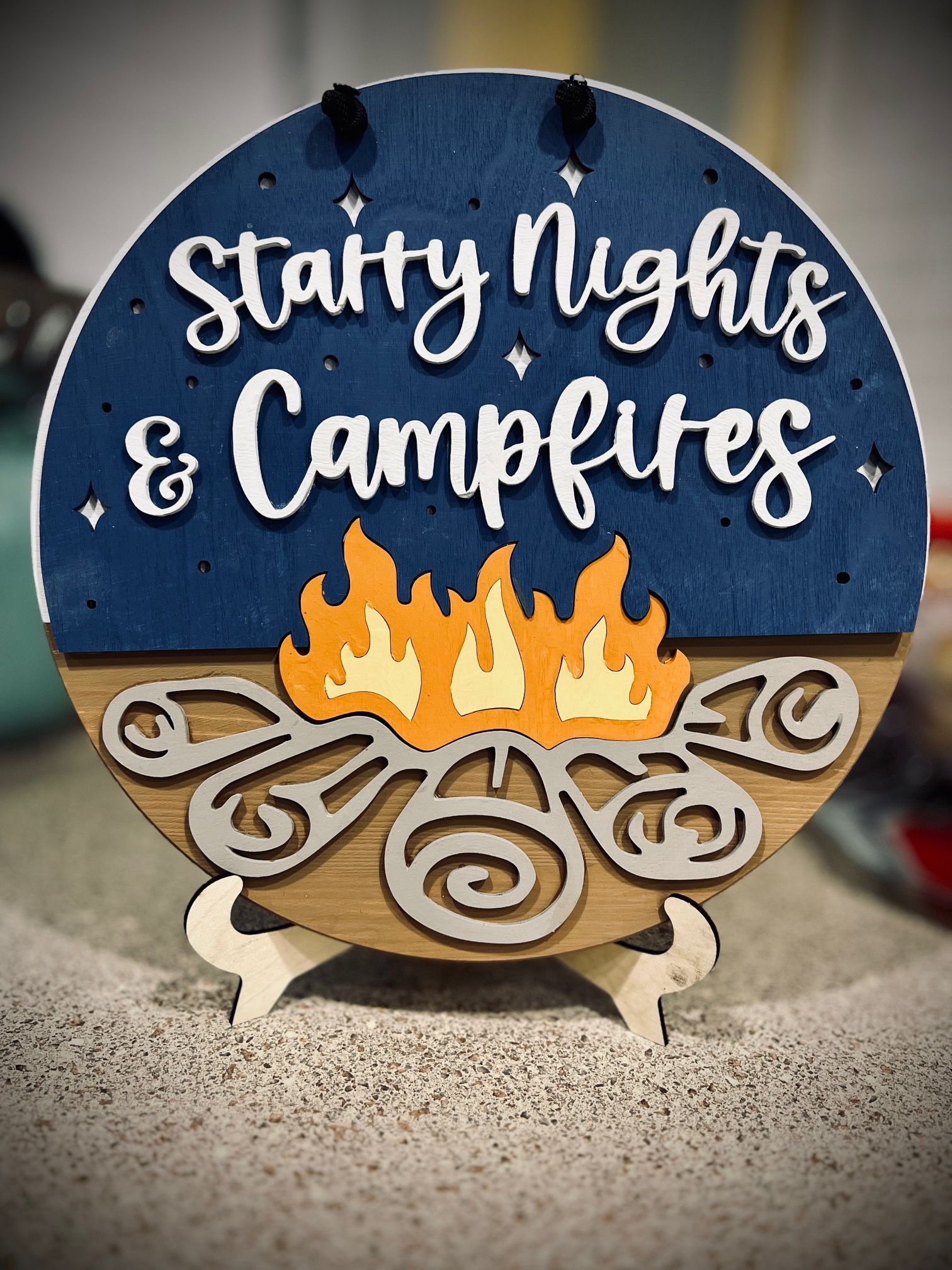 “Starry Nights & Campfires” sign with a campfire illustration and blue background