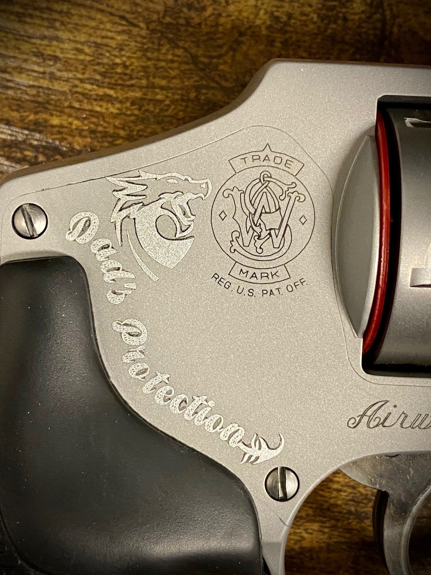 Close-up of a silver revolver with black grip and red cylinder ring on a wooden surface