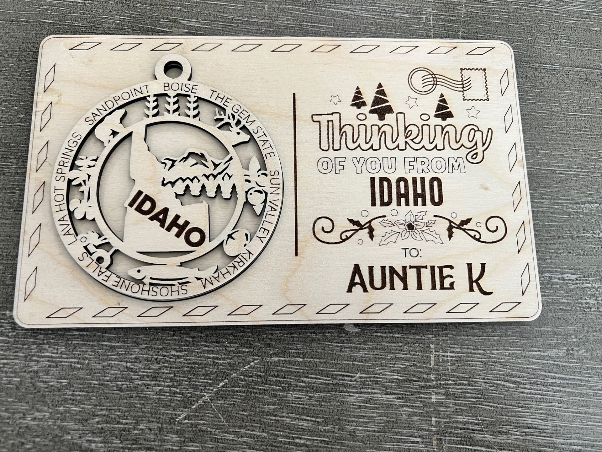 White engraved plaque reading “Thankful for Idaho” and “Auntie K,” with a circular Idaho emblem and mountain deer motif.