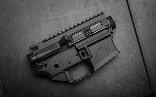 Black AR-15 style rifle receiver on a dark surface, featuring an 